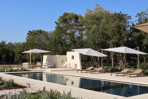 a swimming pool with umbrellas and chairs next to a resort at Quercia Private Nature Retreat in Maglie