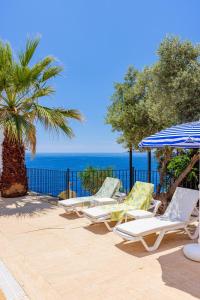 a row of lounge chairs and umbrellas on a beach at Panaroma Meis Suits in Kaş