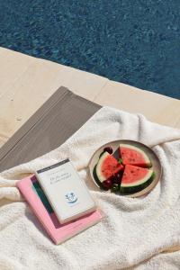 a book sitting on a towel next to a plate of watermelon at Quercia Private Nature Retreat in Maglie