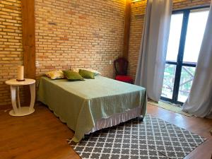 a bedroom with a bed and a brick wall at Chalé Suíça da Serra in São Benedito