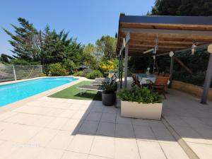 a patio with a table and chairs next to a pool at La symphonie des oiseaux in Villelongue-dʼAude