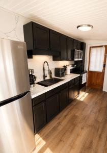 a kitchen with black cabinets and a stainless steel refrigerator at The Cozy Corner House in Kissimmee