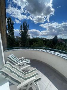 two lounge chairs sitting on a balcony with a view at Veľký rodinný apartmán s výhľadom na zeleň a hory v centre Piešťan s parkovaním in Piešťany +4 photos