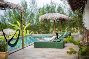 a woman sitting on a green couch next to a pool at Pura Vida Hotel in Itarema