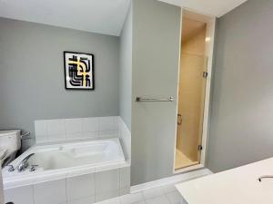 a bathroom with a white tub and a shower at The Grand Maple Residence in Brampton