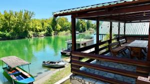 a house with a deck with a boat on a river at Laki House Skadar lake in Železnička Stanica Zeta