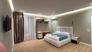 a bedroom with a large white bed and a television at Gysi`s Hotel & Restaurant - Near Tirana in Tapizë
