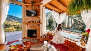 a woman standing in front of a tub in a house at Chalé Caminho do Sol in Rancho Queimado