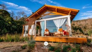 a woman standing on the porch of a tiny house at Chalé Caminho do Sol in Rancho Queimado