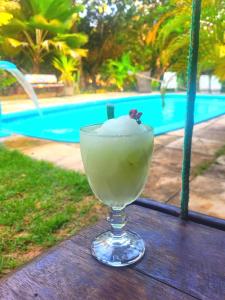 a drink sitting on a table next to a pool at Urca do Tubarão in Touros