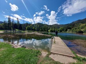 a man standing on a wooden bridge over a lake at La symphonie des oiseaux in Villelongue-dʼAude