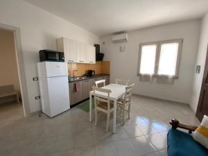 a kitchen with a table and a white refrigerator at Ginestra in Galtellì