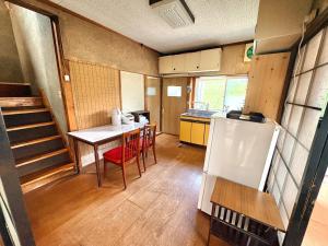 a small kitchen with a table and a refrigerator at 長峰駅から徒歩3分ゲストハウスオオワニ in Ōwani