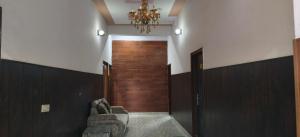 a hallway with a door and a chair and a chandelier at Hotel Golden Spark in Jewar