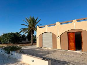 a building with a garage and a palm tree at Dar El Baraka in Ghar el Fabs
