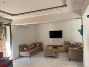 a living room with couches and a flat screen tv at Dar El Baraka in Ghar el Fabs