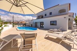 a patio with chairs and an umbrella and a swimming pool at Vivenda Vilhegas in Albufeira