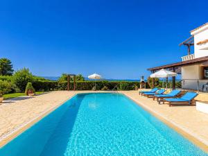 a swimming pool with blue chairs and a house at Villa Argaka Heights in Argaka