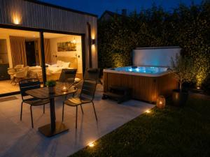 a patio with a hot tub and a table and chairs at Le Cocon, Jacuzzi privé Spa Francorchamps in Spa