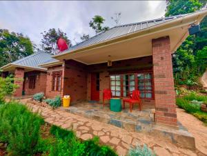 a brick house with red chairs on a patio at Kijani Pazuri Cottages in Lushoto