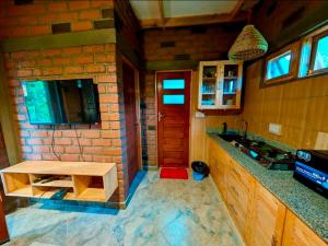 a kitchen with a sink and a brick wall at Kijani Pazuri Cottages in Lushoto +18 photos