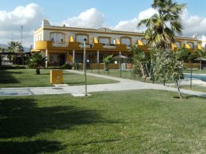 タリファにあるLivingtarifa La Tortuguitaのヤシの木とプールのある黄色い建物