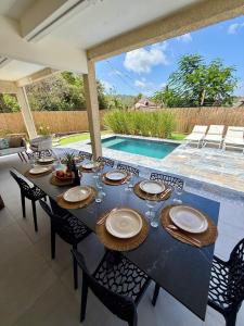 a dining table with plates and wine glasses next to a pool at Villa Ma Cherry in Le Diamant