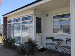 a white house with a table and chairs outside at "Trinity" Chalet in Sundowner Hemsby in Hemsby