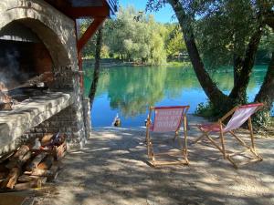 two chairs and a sign in front of a lake at Villa Elaris in Bihać