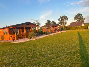 a house with a large grass field in front of it at Domki nad stawem in Sambród
