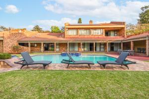 a house with a swimming pool with chairs and a house at Bryanston stays in Johannesburg