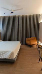 a hotel room with a bed and a chair at Hotel Grande Court in Kharar