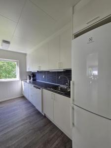 eine weiße Küche mit Spüle und Kühlschrank in der Unterkunft Bergsbu in Senja