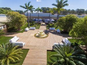 a patio with chairs and a fountain and palm trees at Green Village Hotel e Restaurante in Santa Bárbara do Rio Pardo