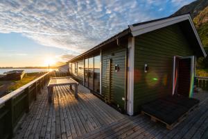 a house on a deck with the sun setting at Lofoten Green House in Ramberg