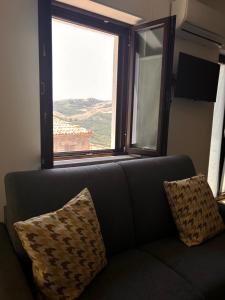 a couch with two pillows sitting in front of a window at Civico 44 in Castelmezzano