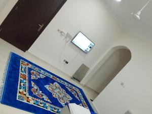 a room with a blue rug and a tv on the ceiling at Mohammad hostel in Ma‘ābīlah