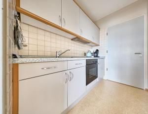 a kitchen with white cabinets and a sink at Haus Schildt, FeWo 5 in Duhnen