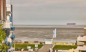 a view of the beach with a cruise ship in the distance at Haus Schildt, FeWo 5 in Duhnen +5 photos