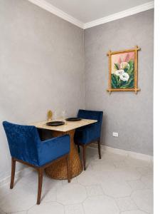 a table with blue chairs and a picture on the wall at Cantinho Da Go in Caraguatatuba