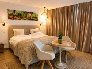 a bedroom with a bed and a table and chairs at Le Cocon, Jacuzzi privé Spa Francorchamps in Spa +13 photos