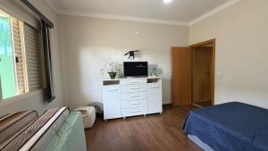 a bedroom with a bed and a tv on a dresser at Refúgio com Piscina e Vista Deslumbrante in Caconde