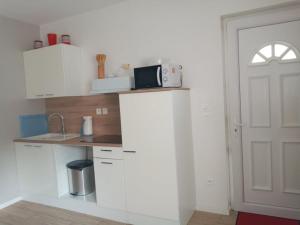 a white kitchen with a microwave on top of a counter at Studio à louer in Vic-Fezensac
