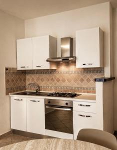 eine Küche mit weißen Schränken und einem Herd mit Backofen in der Unterkunft Ā - Living in Valledoria
