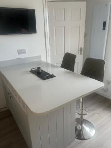 a white desk with two chairs in a room at Coastal Charm Seaside House in Moelfre