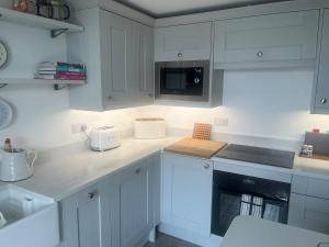 a kitchen with white cabinets and a counter top at Coastal Charm Seaside House in Moelfre