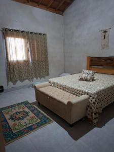 a bedroom with a bed and a couch and a window at Chalé Araucárias-Recanto dos pássaros in Cambuí