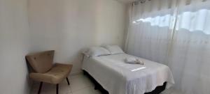 a small bedroom with a bed and a chair at Pousada Girassol Genipabu in Extremóz