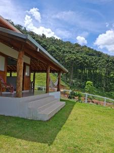 a house with a porch and stairs in the grass at Chalé Araucárias-Recanto dos pássaros in Cambuí