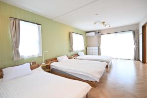 three beds in a room with green walls and windows at Fuka in Beppu -New Open January2026 in Beppu